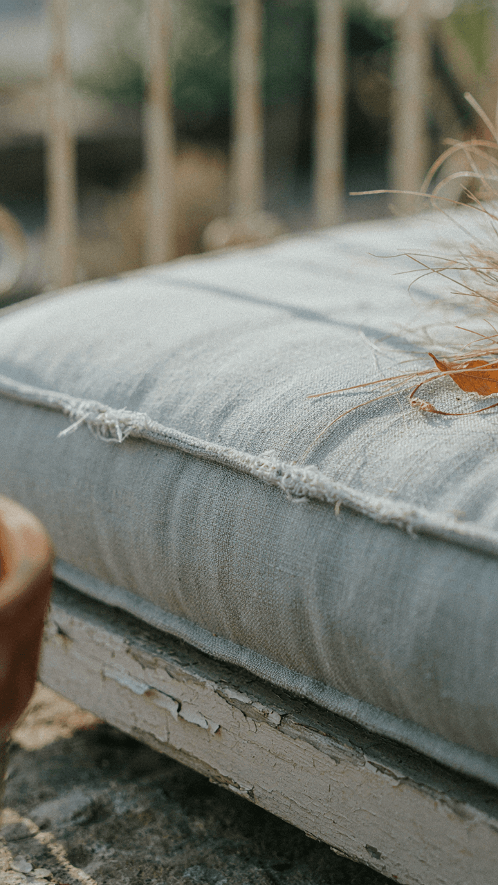 A sun-damaged outdoor daybed cushion shows cracks and fading.