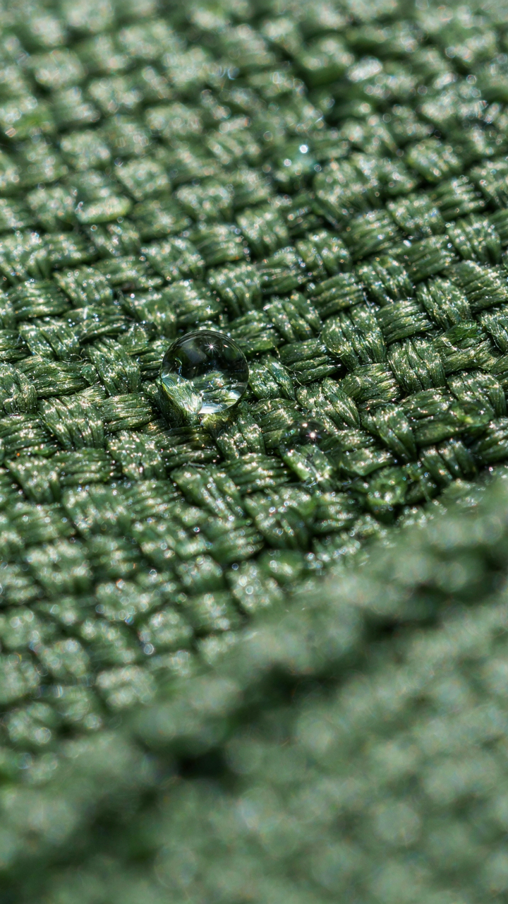 A single water droplet sits on a picnic mat, not soaking into the fabric.