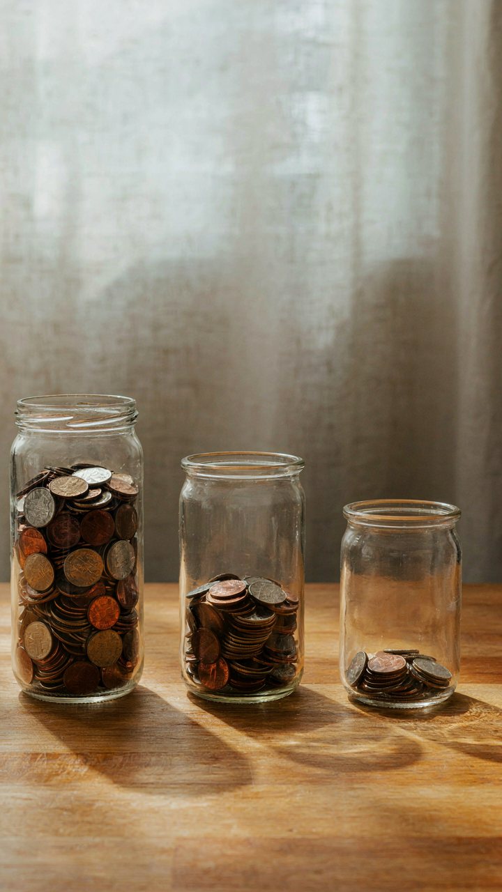 Three glass jars labeled for different tiers, each with coins.