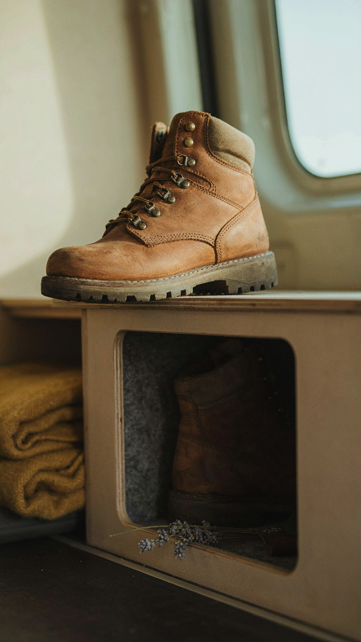 A person carefully considers putting a hiking boot into a van storage space.