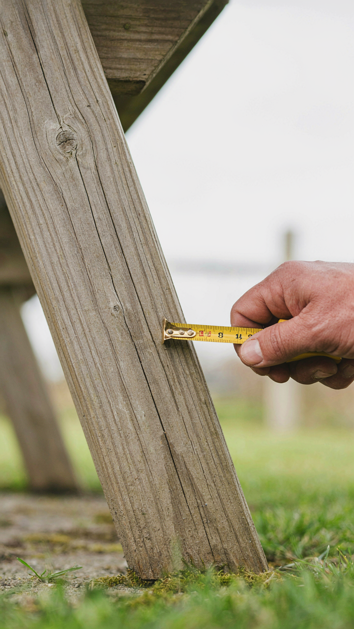 A hand inspecting a picnic table for structural damage.
