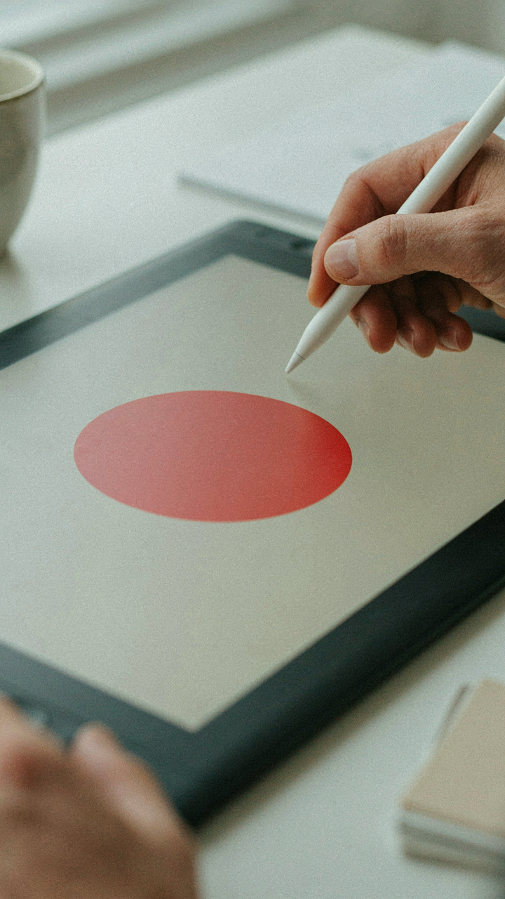 A hand using a stylus on a tablet, highlighting a single design element.