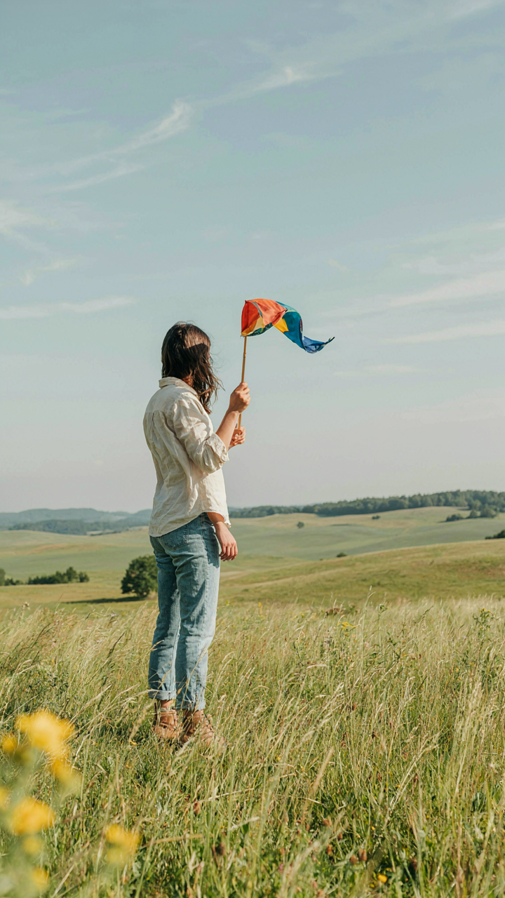 A person watches a windsock blowing in a field to understand wind direction.