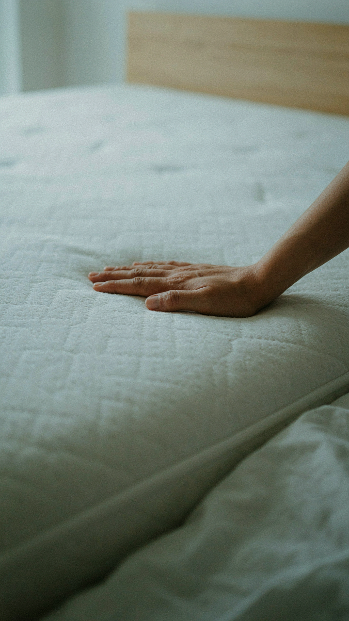 A hand presses into a dense foam mattress, showing its conforming quality.