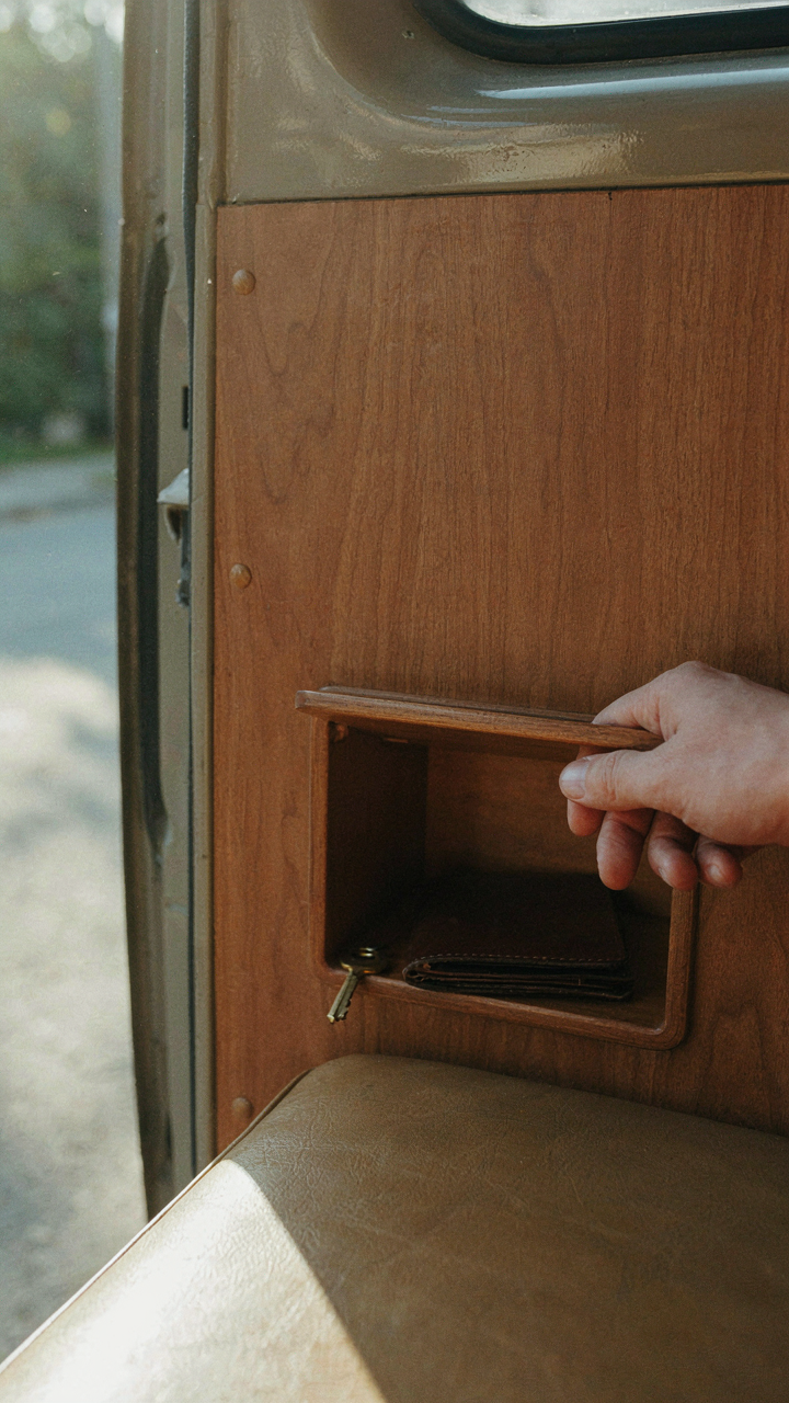 A hand opens a hidden, secure compartment inside a van.
