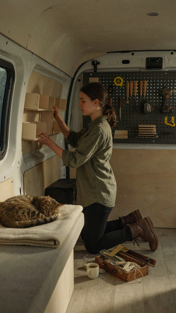 A person customizes a modular shelf system inside a small camper van.