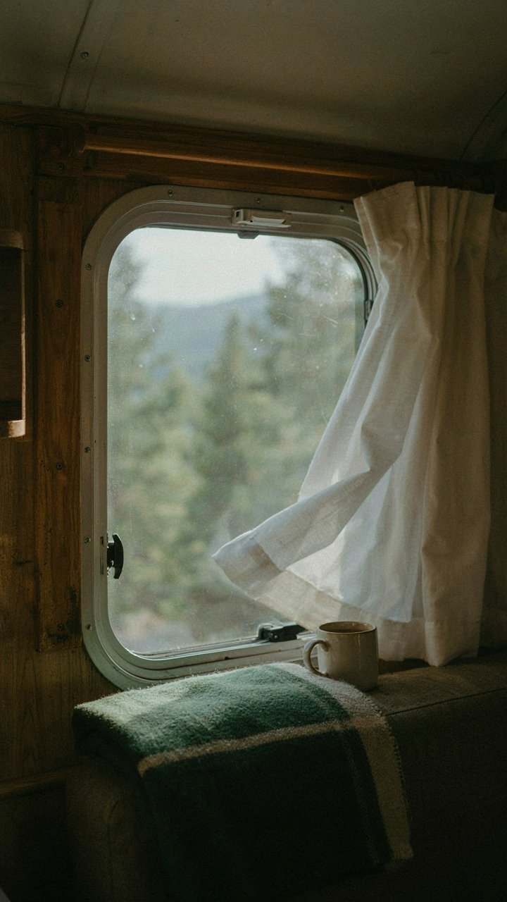 A small RV window is open a crack for ventilation on a cold day.