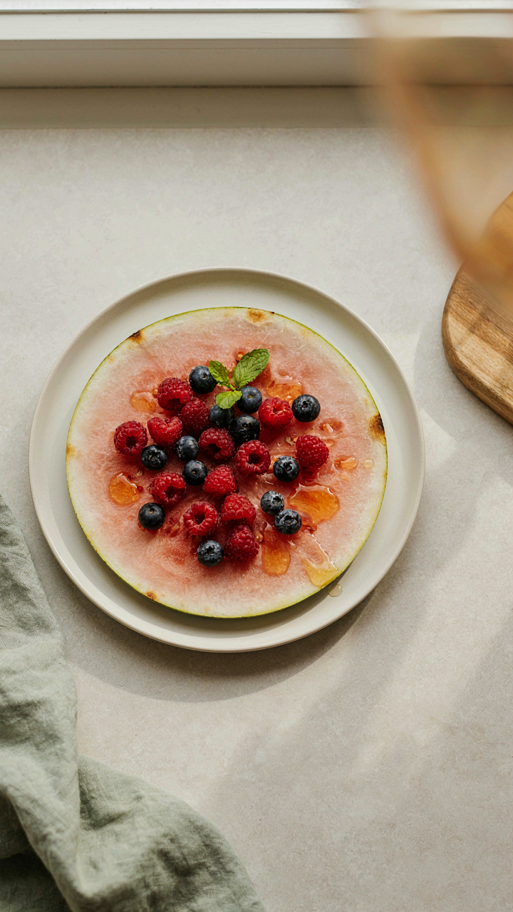A simple watermelon pizza with berries and honey.