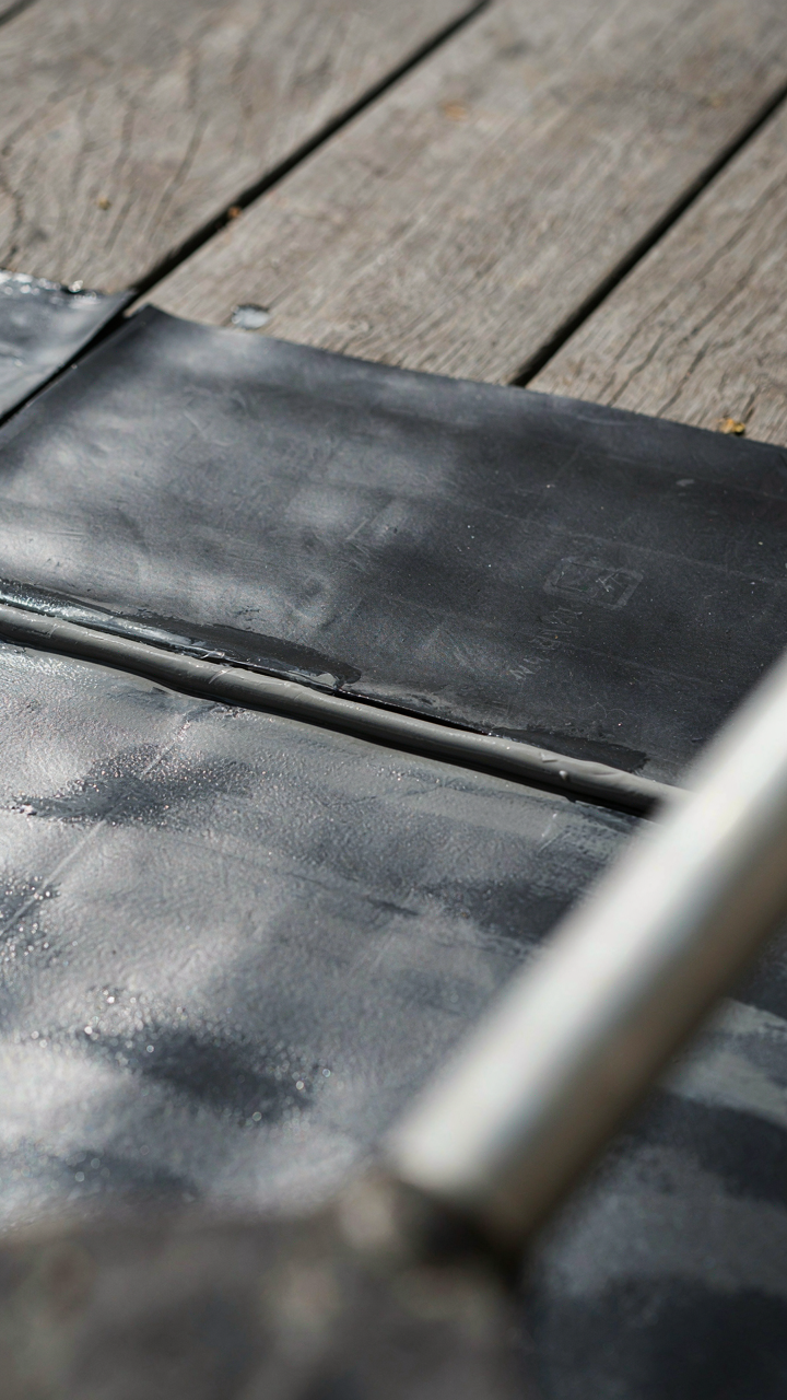 Multiple layers of waterproof membrane and sealant cover a wooden surface.