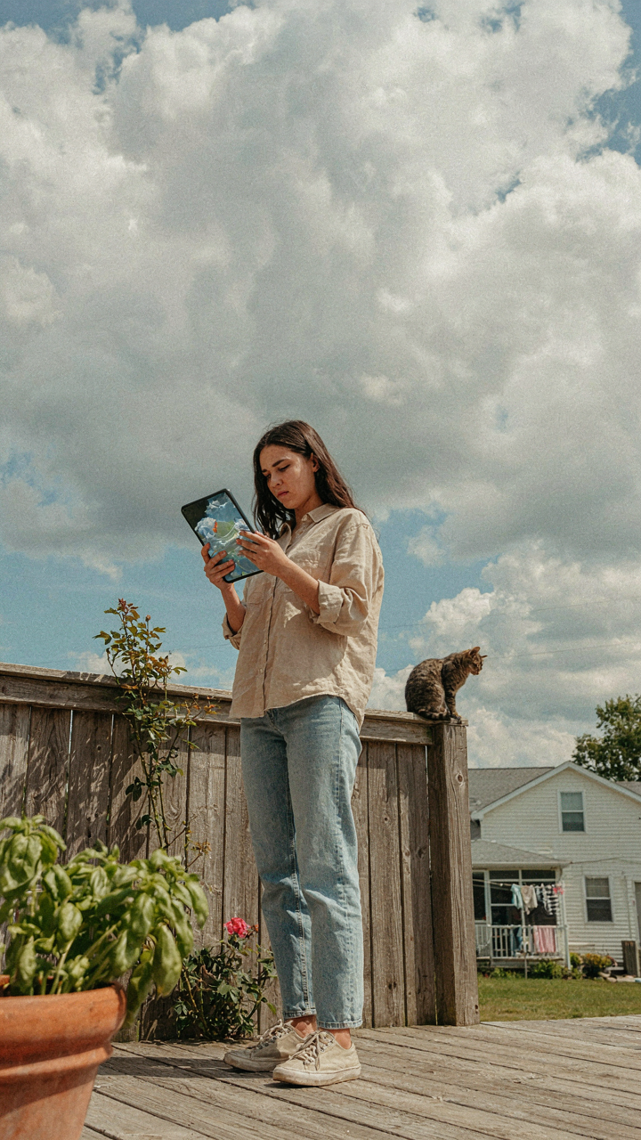 Someone checks weather on a tablet, looking at a cloudy sky.