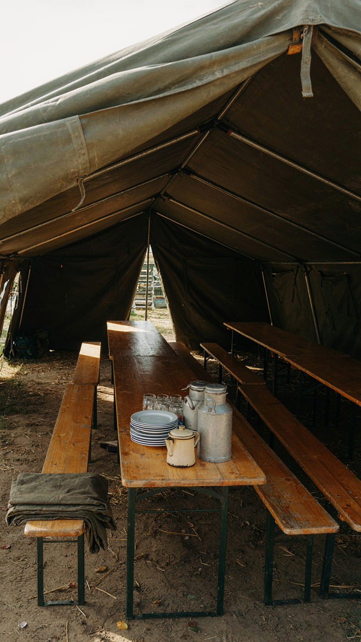 A large military field tent set up with dining tables and benches inside.