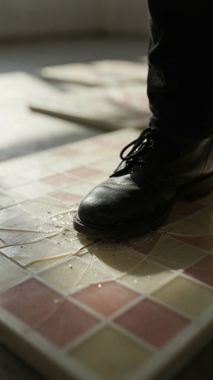 A cheap plastic dance tile is broken under a heavy boot.