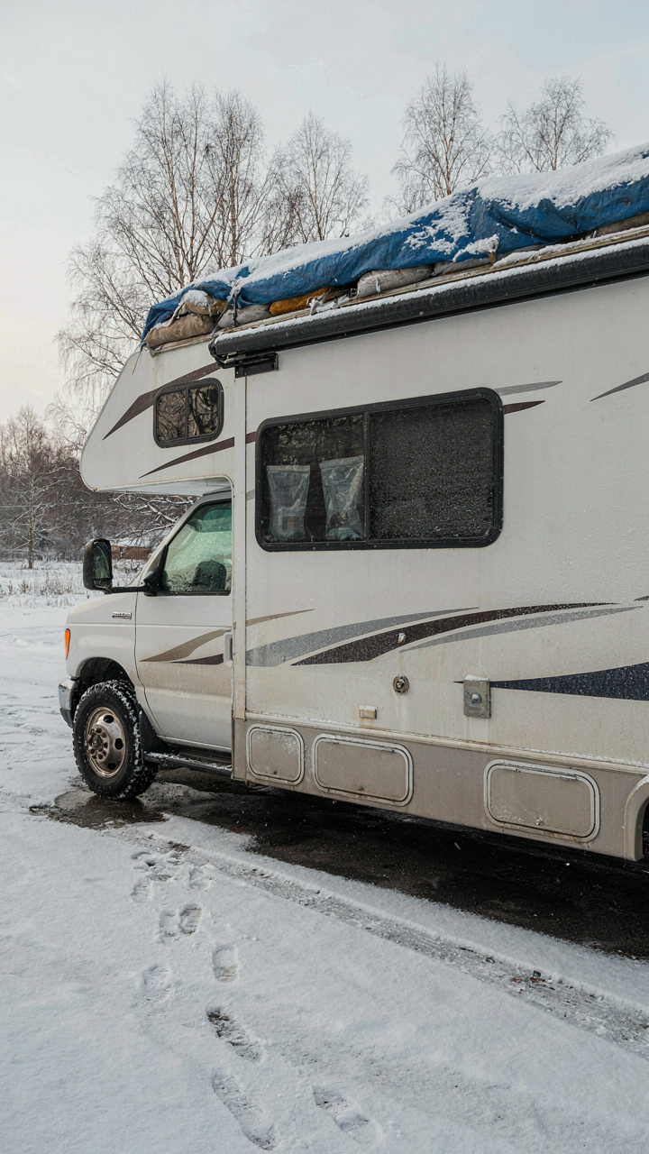 An RV under a winter tarp, with partially effective moisture absorbers inside.