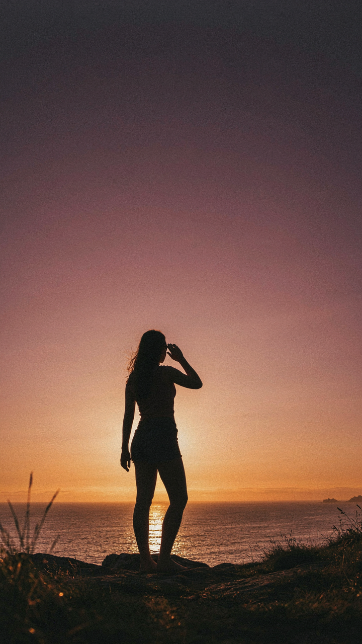 A person watching the sun rise over the ocean, bathed in natural light.