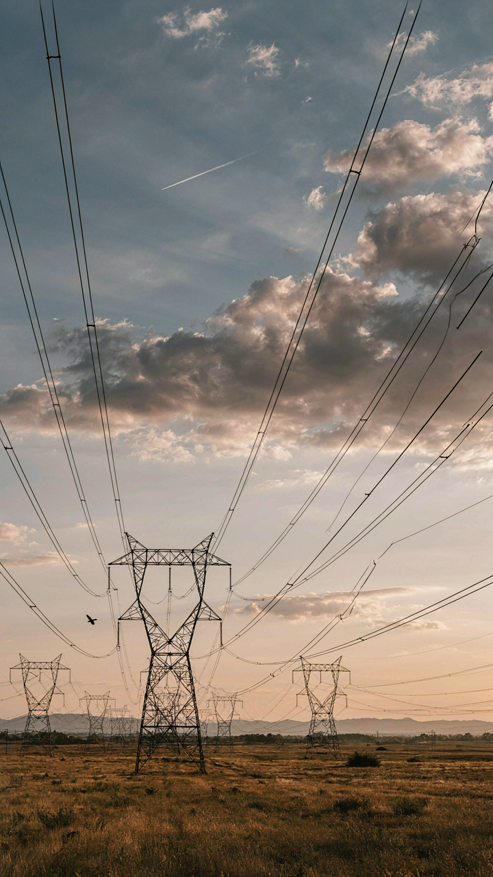 A complex web of electrical power lines stretches across a sunset sky.