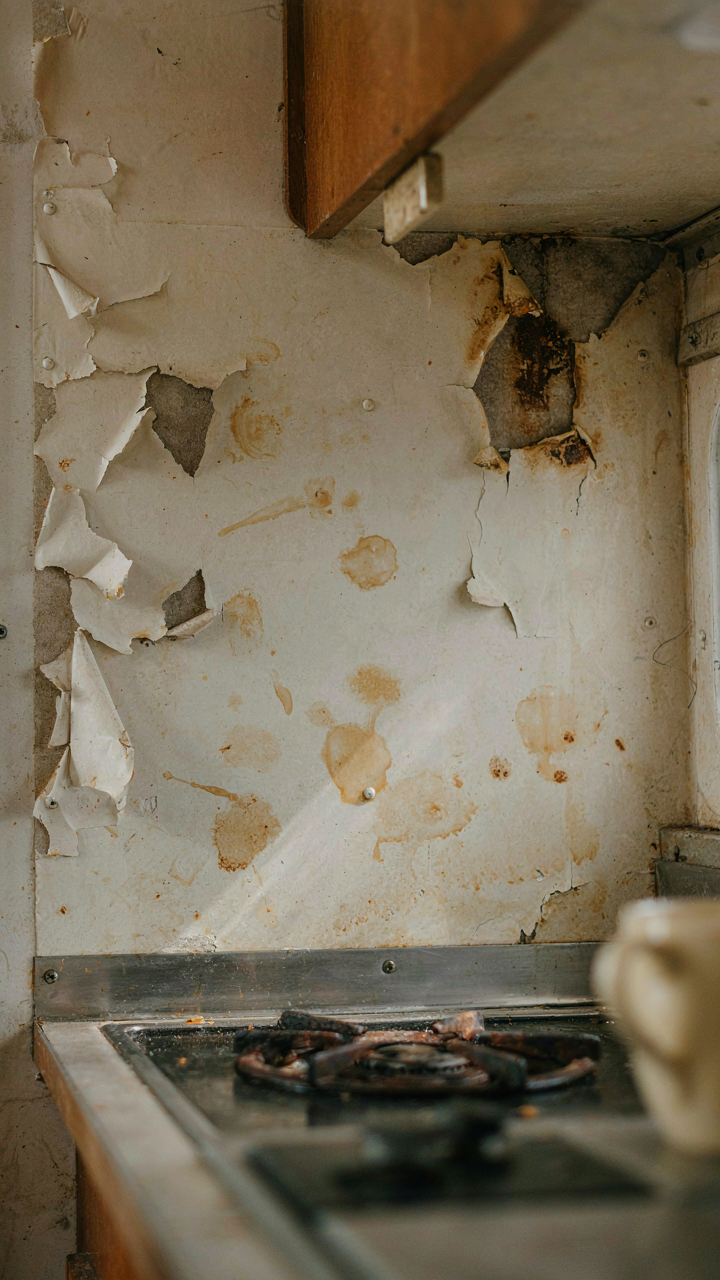 A close-up view of a badly damaged wall behind a small RV kitchen counter.