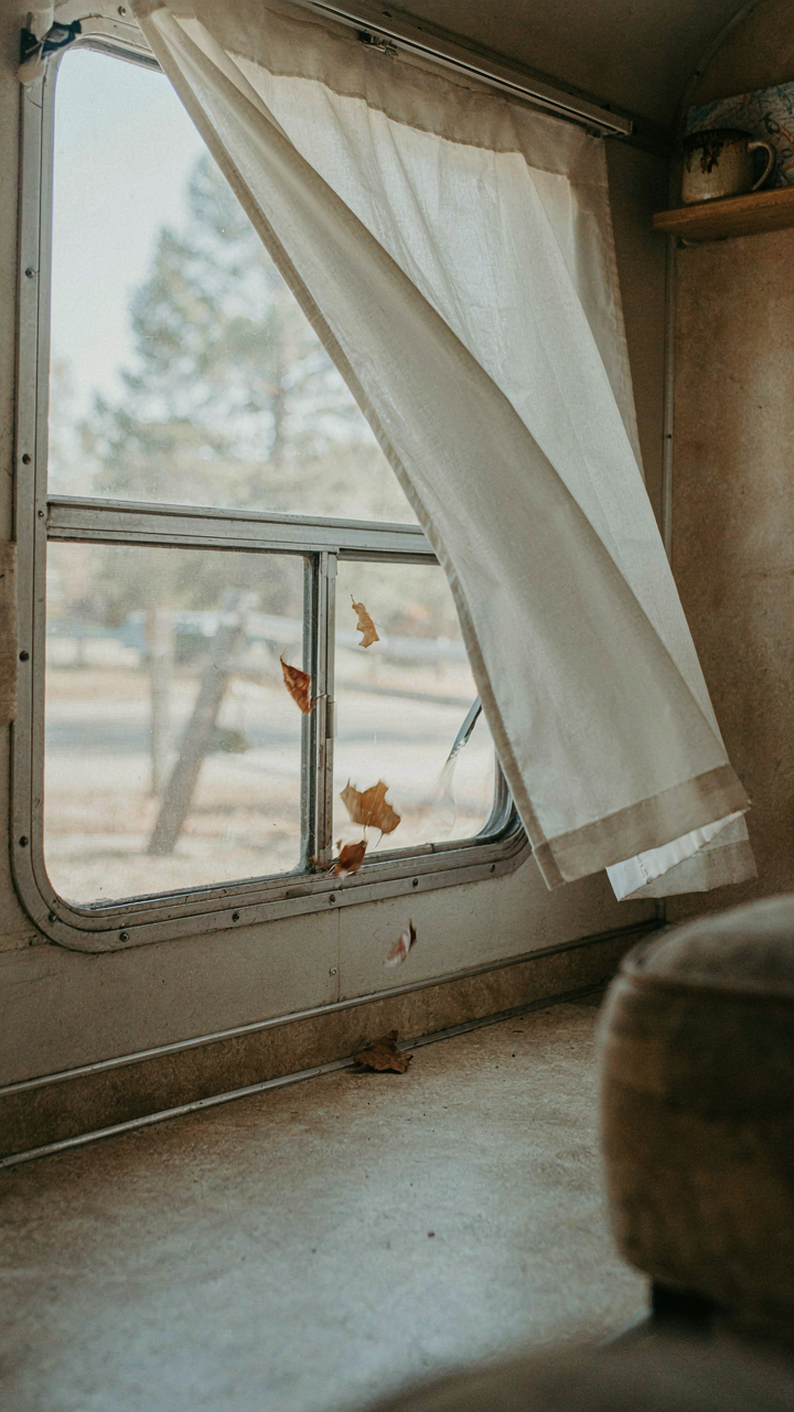 Cold wind blows a flimsy curtain away from an RV window.